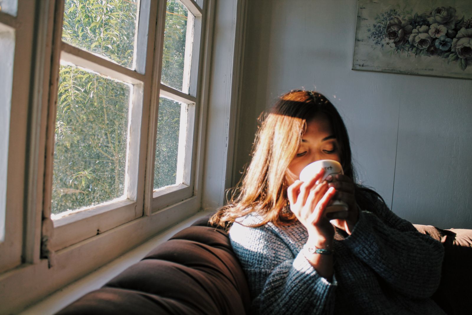 A person sitting by a window, peacefully enjoying a warm drink